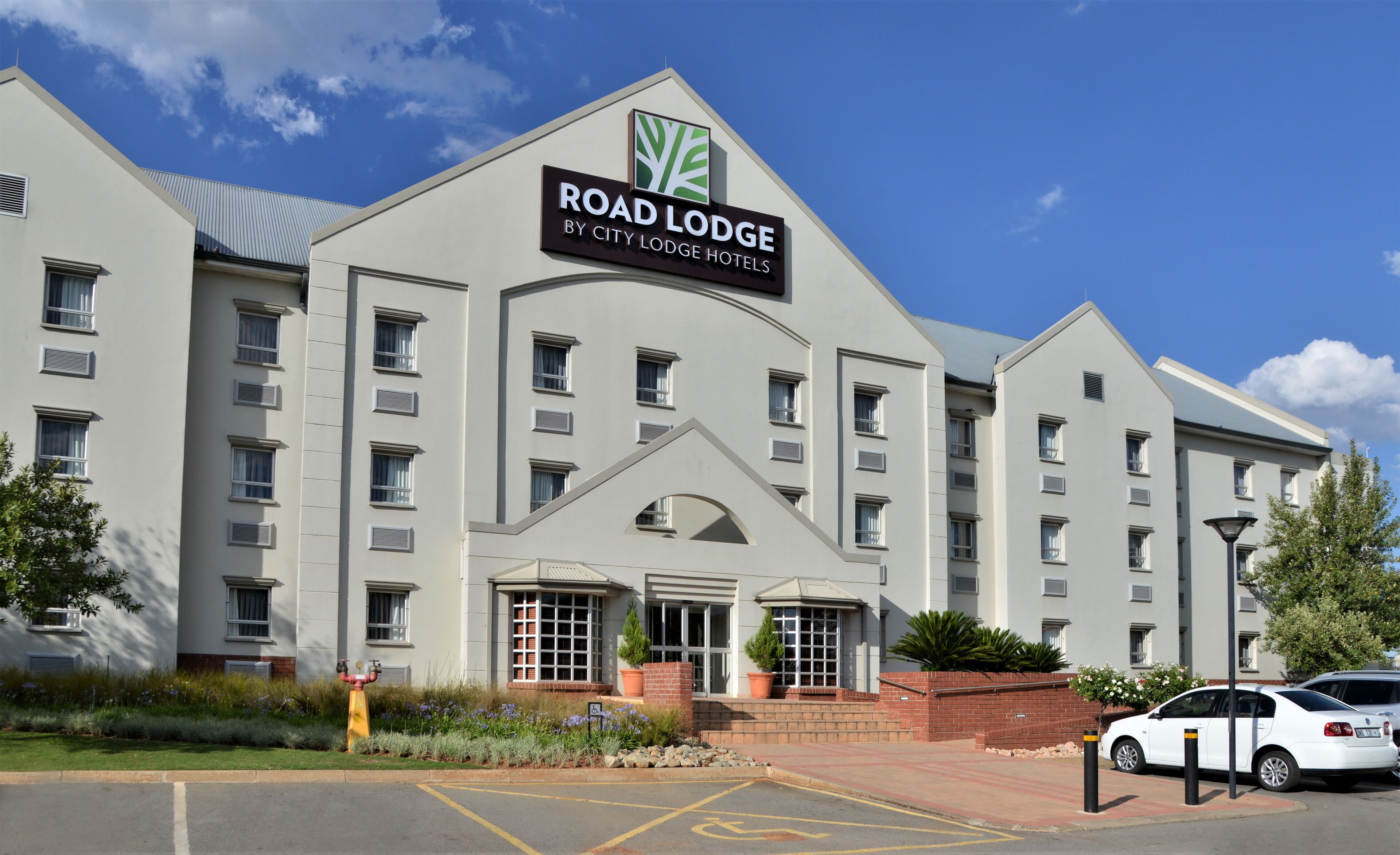 A modern hotel building with a prominent sign reading "ROAD LODGE BY CITY LODGE HOTELS".