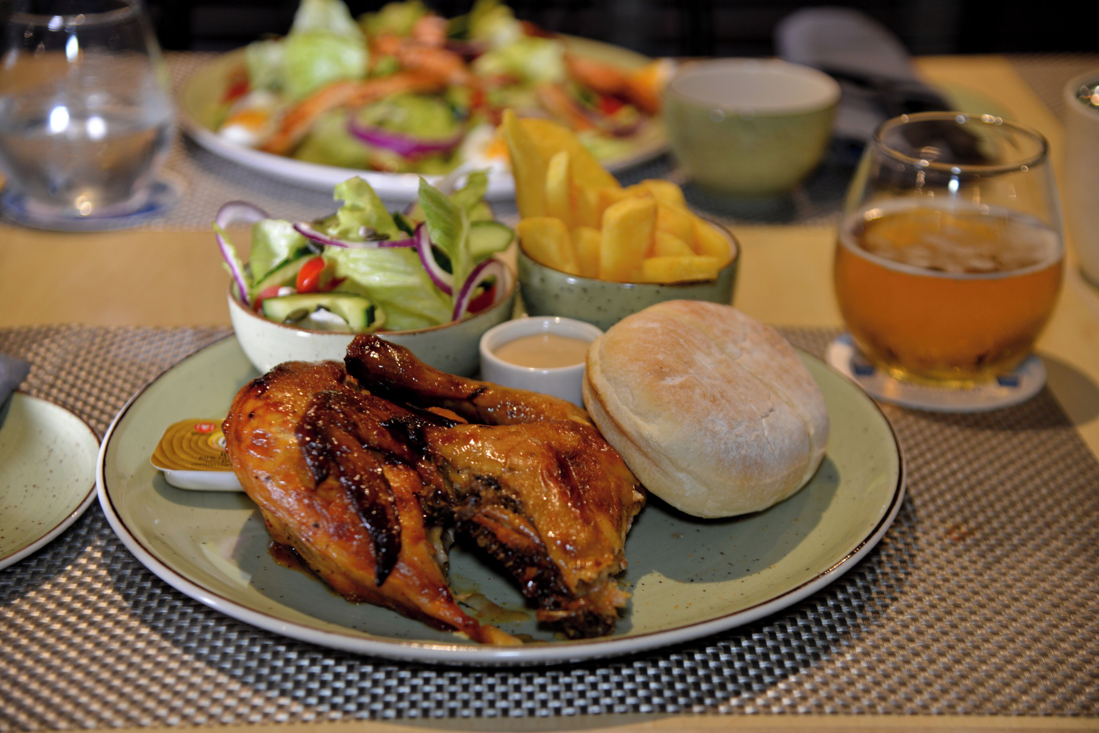 Een bord met gebraden kip, een salade, frieten en een koekje.