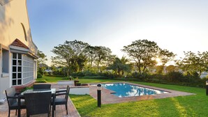 A swimming pool with a brick border, surrounded by a grassy lawn and trees. - Road Lodge Richards Bay (Richards Bay)