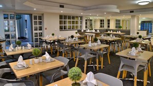 A dining area with multiple tables, chairs, and neatly arranged napkins.