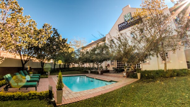 A hotel with a swimming pool, outdoor seating, and a sign reading "Roadhouse by City Lodge Hotels".