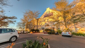 A hotel with a prominent sign, a parking lot, and surrounding trees.