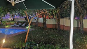 A covered outdoor area with a pool, lounge chairs, and a table with a candle.
