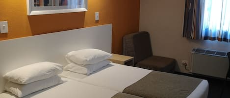 Una habitación de hotel con una cama grande, una silla, un escritorio y un ventanal con cortinas.