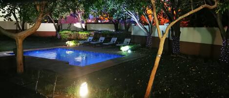 An outdoor pool area with lounge chairs and a tiled deck.