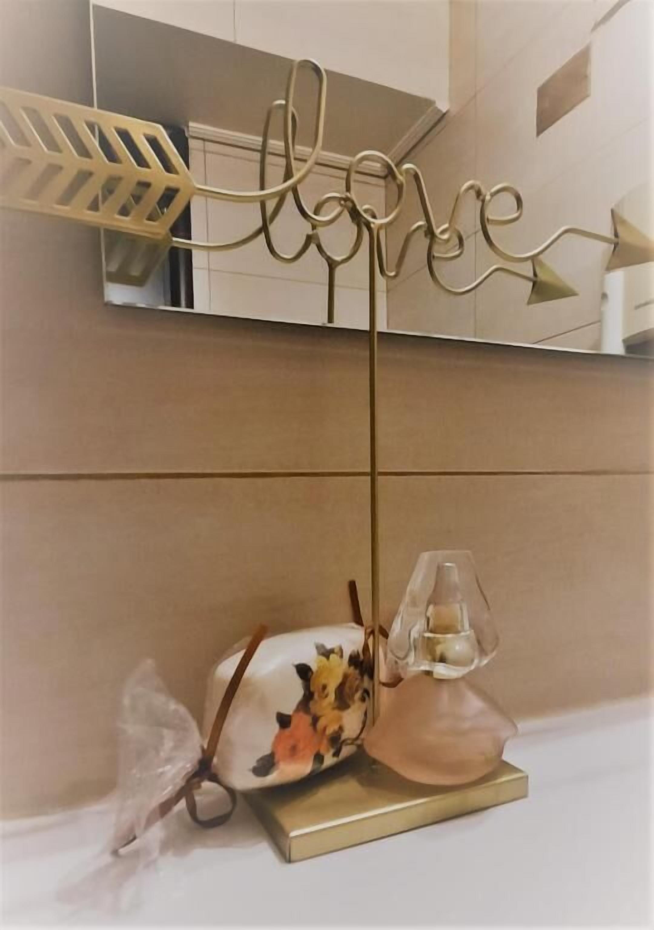 A decorative wall piece with the word "love" and arrows, a small table with a lamp, and a floral-patterned bag.