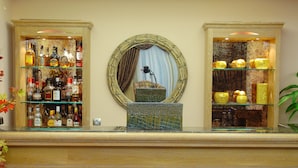 A bar area with a tiled floor, a mirror, and shelves with bottles. - Olympic Fashion Hotels (Chalandri)