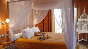 A hotel room with a bed, a nightstand, a tray with tea and sugar, and a decorative birdcage. - Olympic Fashion Hotels (Chalandri)