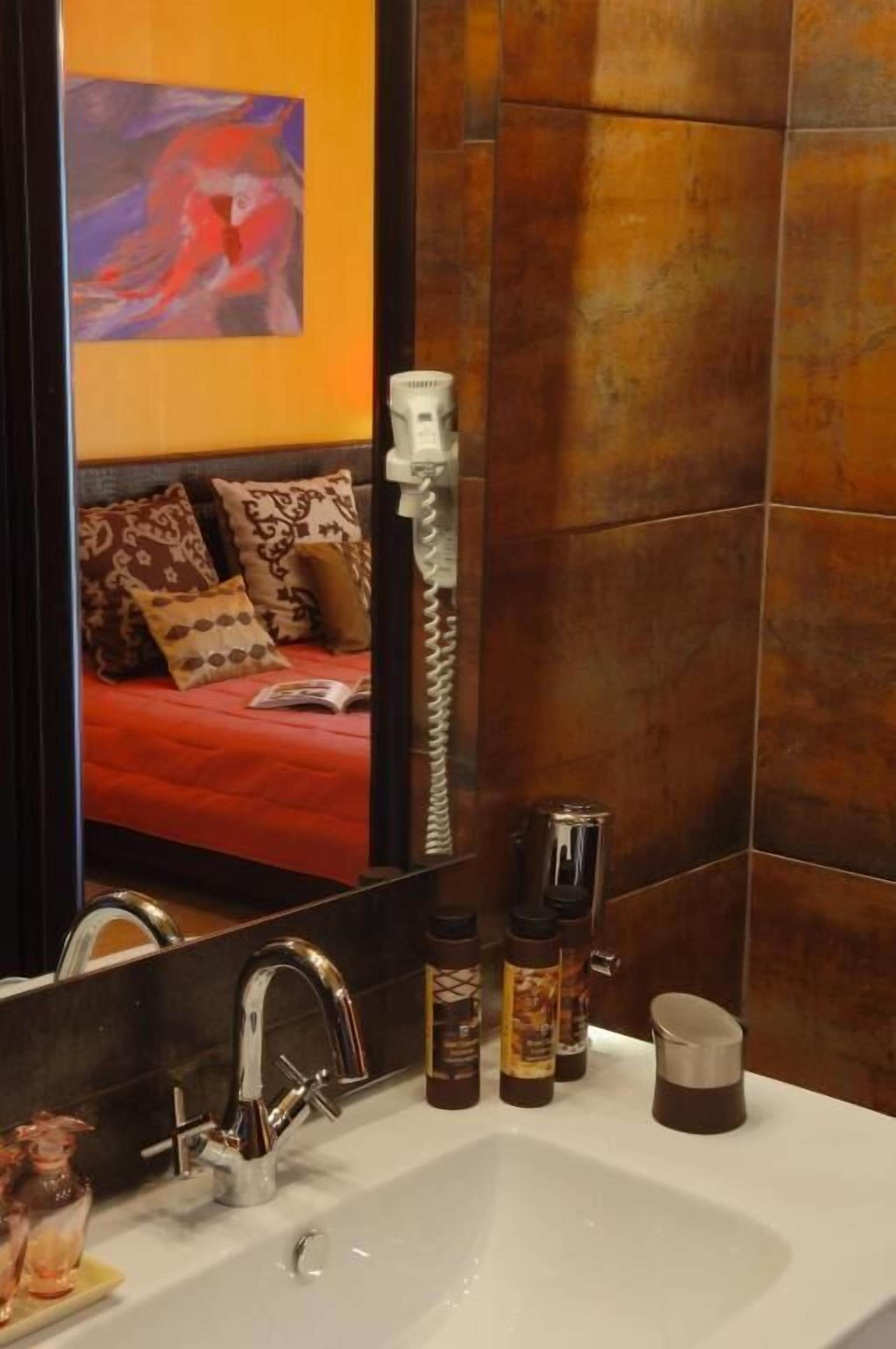 A bathroom with a large mirror, a white sink, and toiletries.