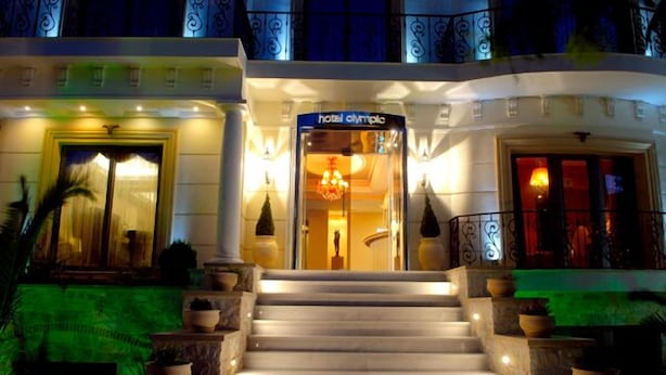 A hotel entrance with a grand staircase, a reception desk, and a chandelier. - Olympic Fashion Hotels (Chalandri)