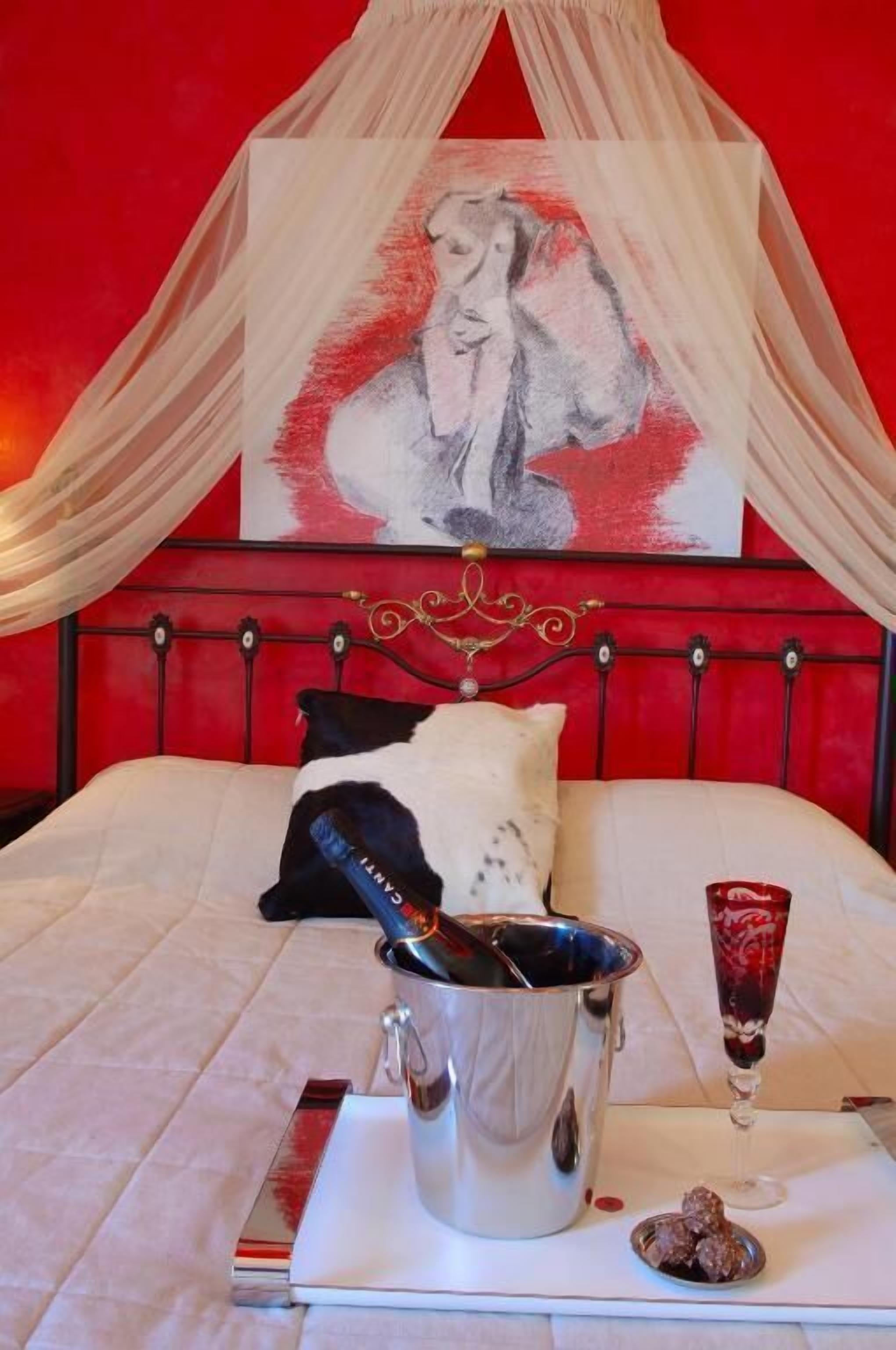 A bed with a red headboard, a white canopy, and a painting above it.