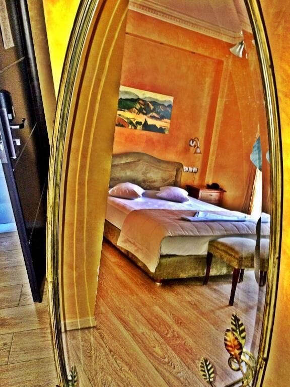 A bedroom with a bed, pillows, a bedside table, and a painting on the wall.