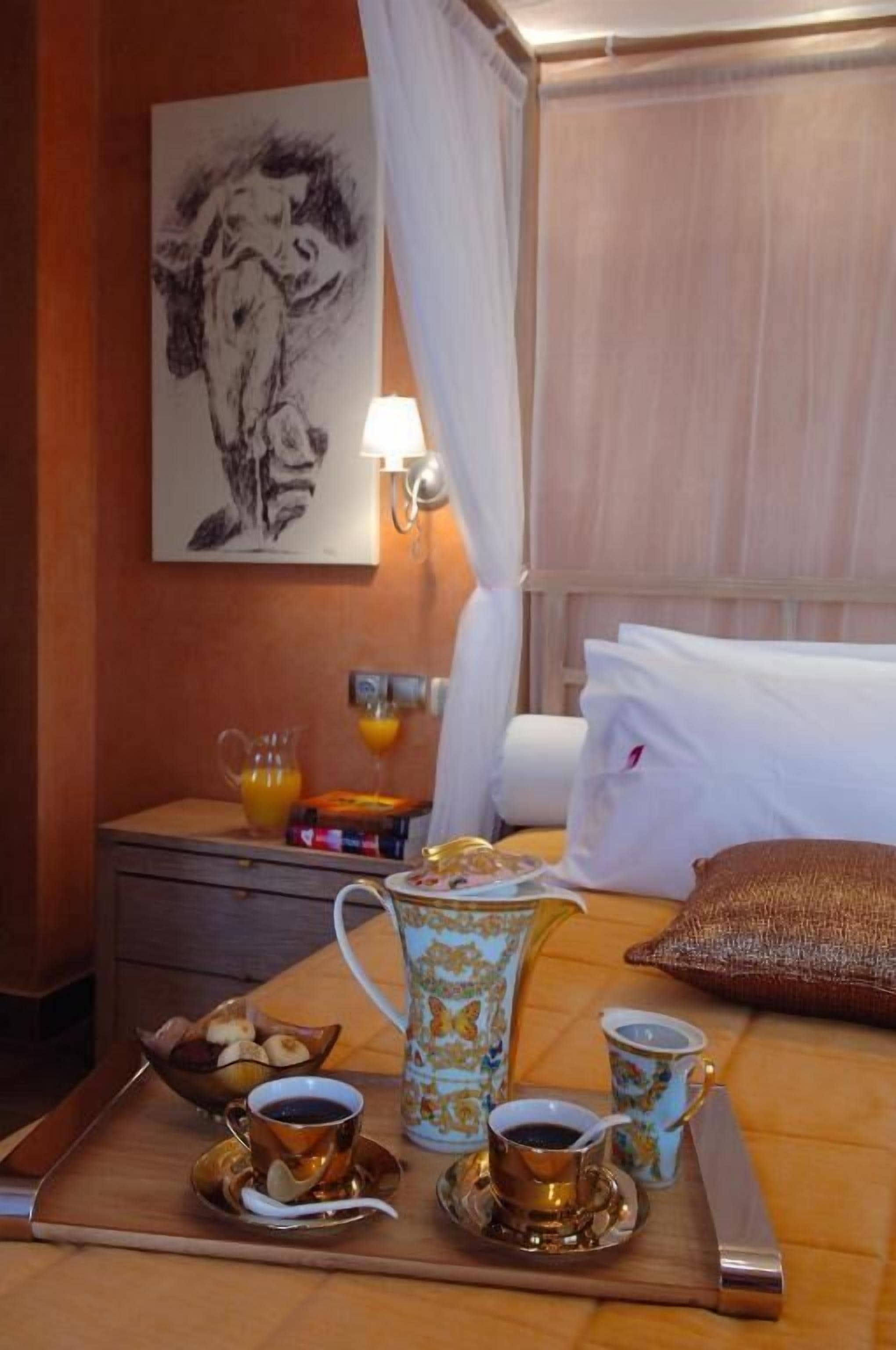 A neatly arranged breakfast tray with coffee cups, a pitcher, and a bowl of fruit on a wooden table in a hotel room.