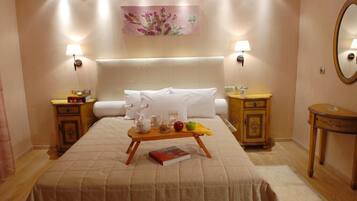 Habitación de hotel con una cama grande, mesitas de noche con lámparas, un cuadro en la pared y un espejo a la derecha.