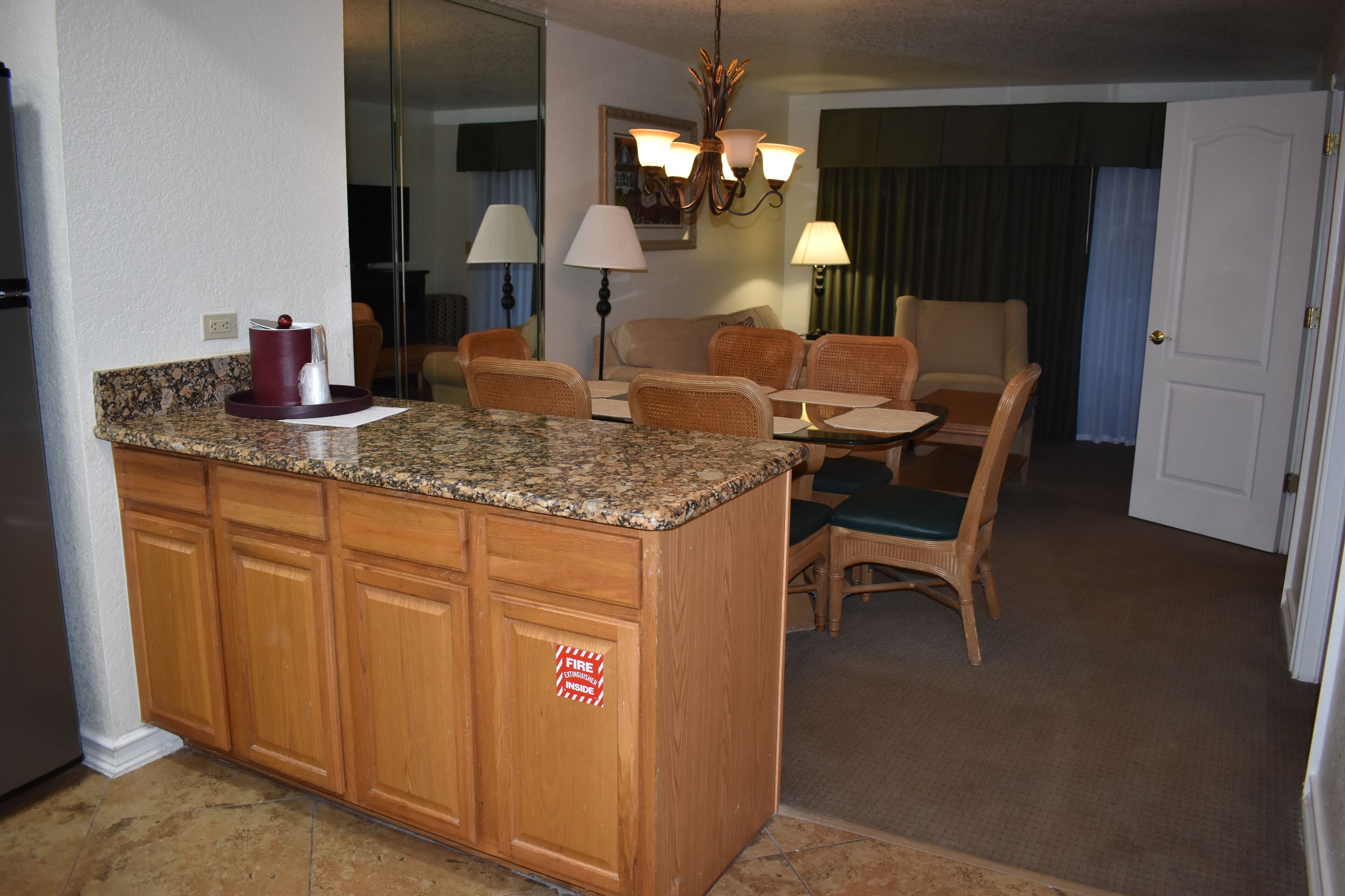 A kitchen with a granite countertop, wooden cabinets, and a fire exit sign.