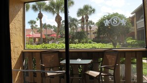A view from a balcony with a table and chairs, overlooking a courtyard with palm trees and buildings. - Club Sevilla (Kissimmee)
