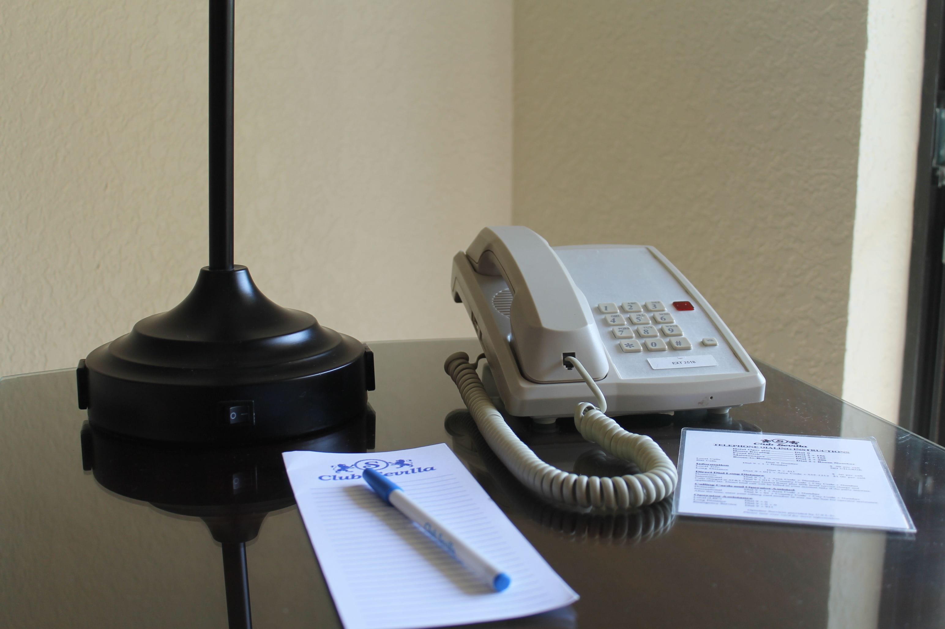 Bancada de recepção de hotel com telefone, bloco de notas e caneta.