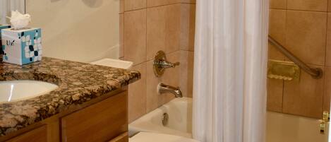 A bathroom with a toilet, sink, and shower area.