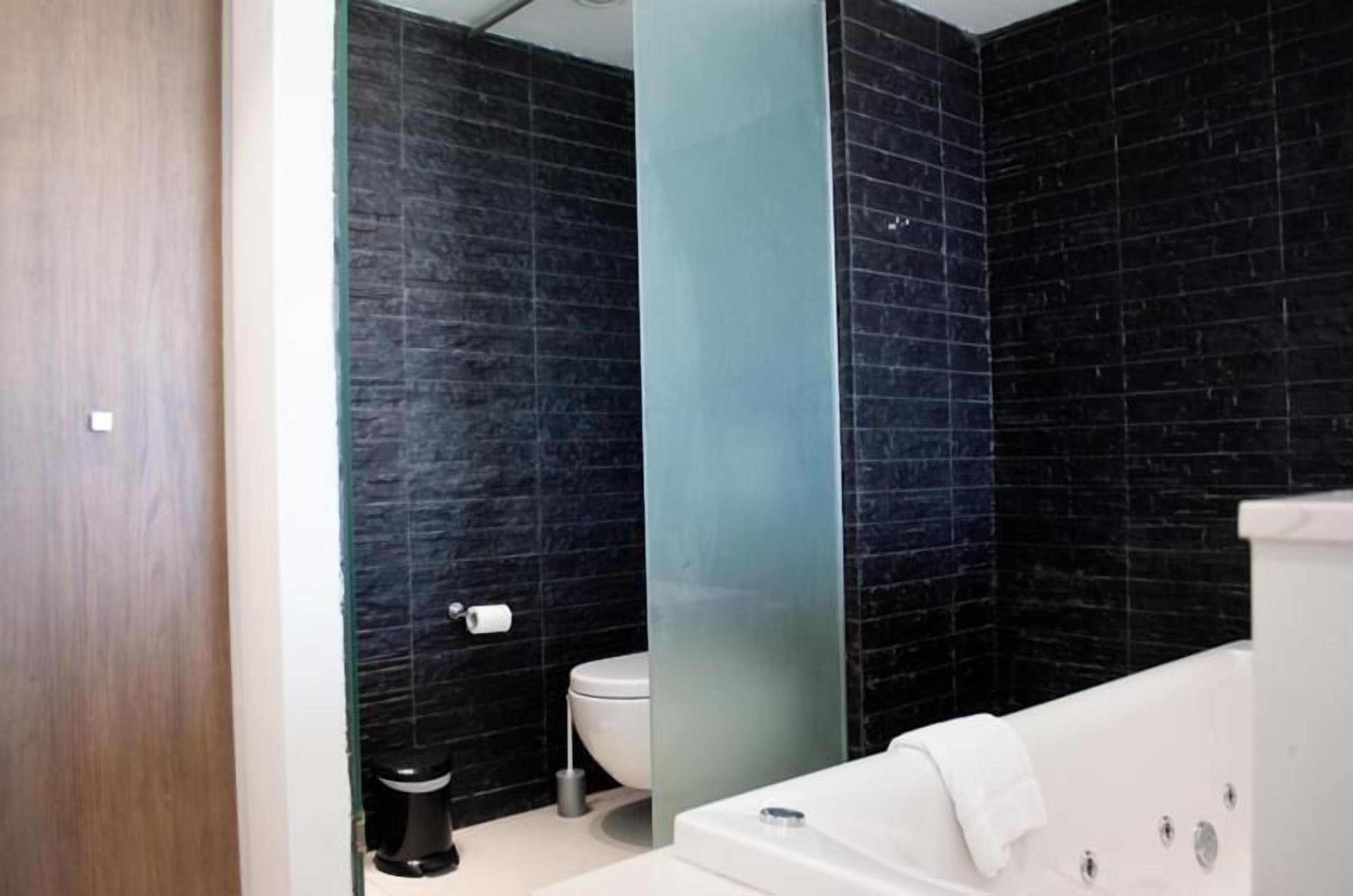 Une salle de bain moderne équipée de toilettes, d’une baignoire et d’une douche à paroi de verre.