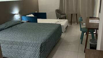 Una habitación de hotel con una cama grande, un escritorio, una silla y una mesita.