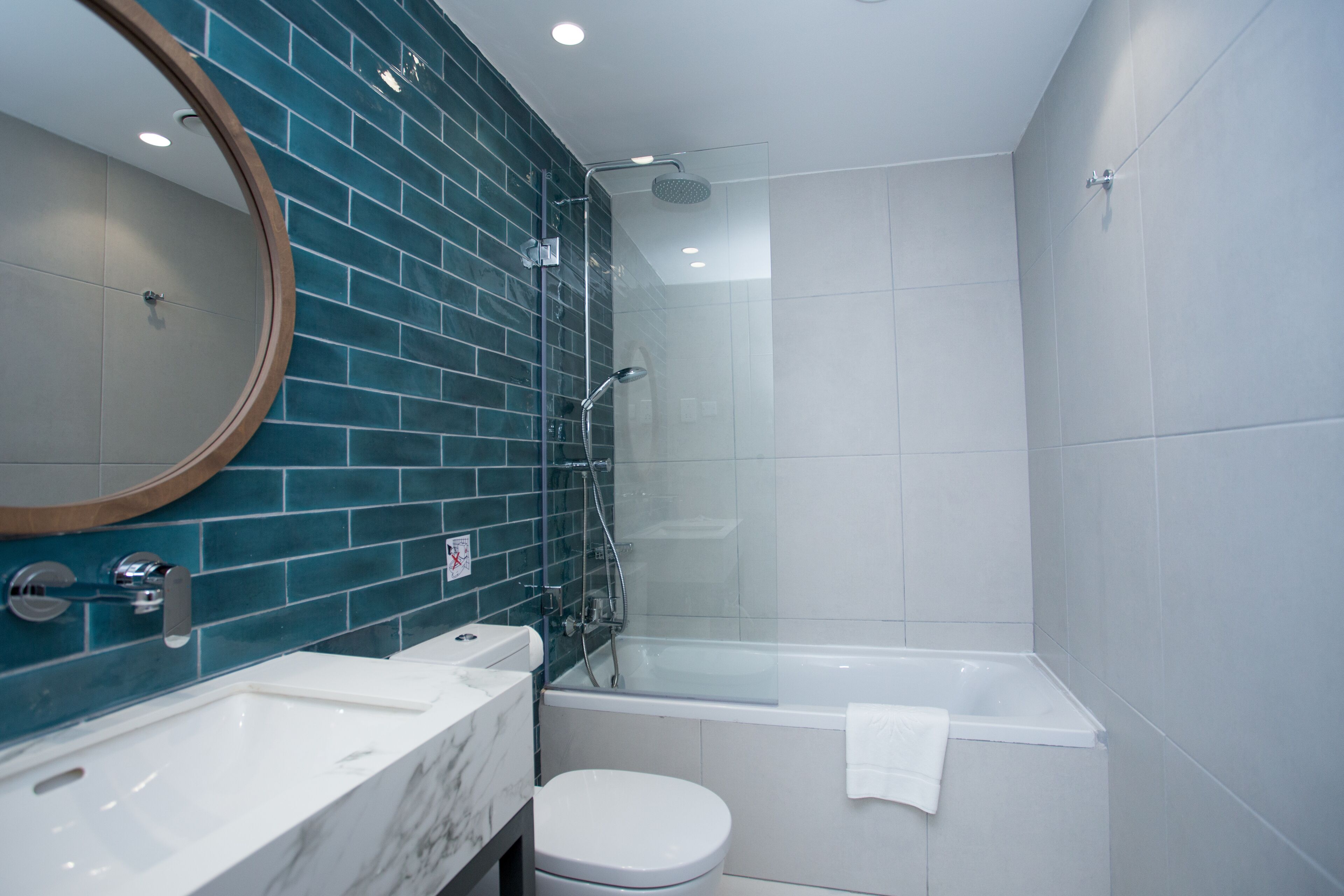 A modern bathroom with a glass-enclosed shower, a white toilet, and a marble sink.