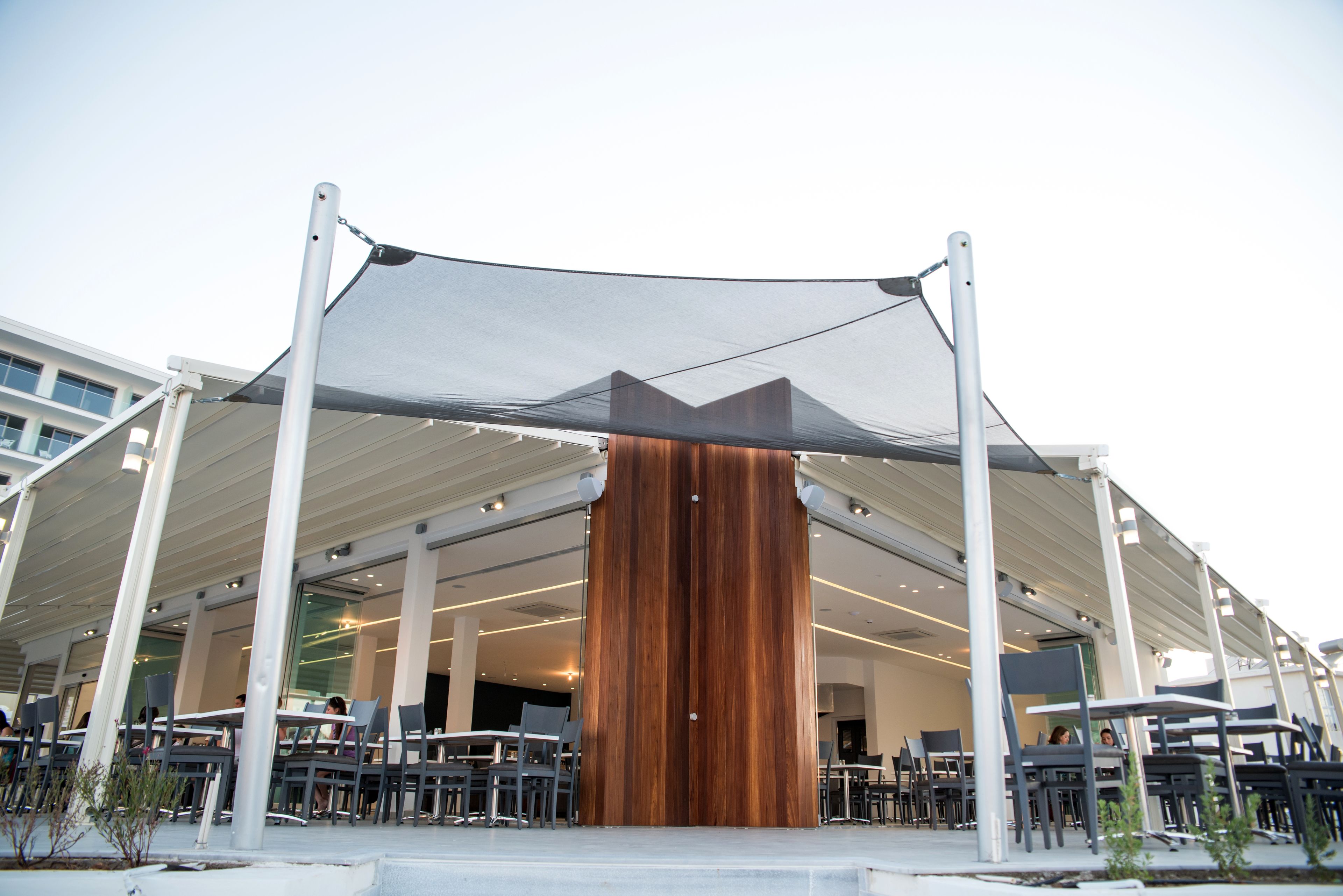 An outdoor seating area with tables and chairs under a large canopy.