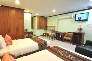 A hotel room with two beds, a desk, a chair, a television, and a wardrobe. - Sky Suites (Bangkok)