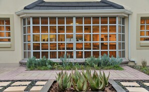 Un edificio con un amplio ventanal y un jardín con plantas al frente.