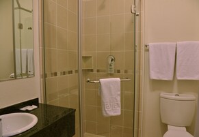 A bathroom with a glass-enclosed shower, a white sink, and two white towels hanging on a rack.