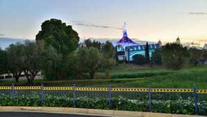 A building with a dome and a spire, surrounded by trees and a fence.