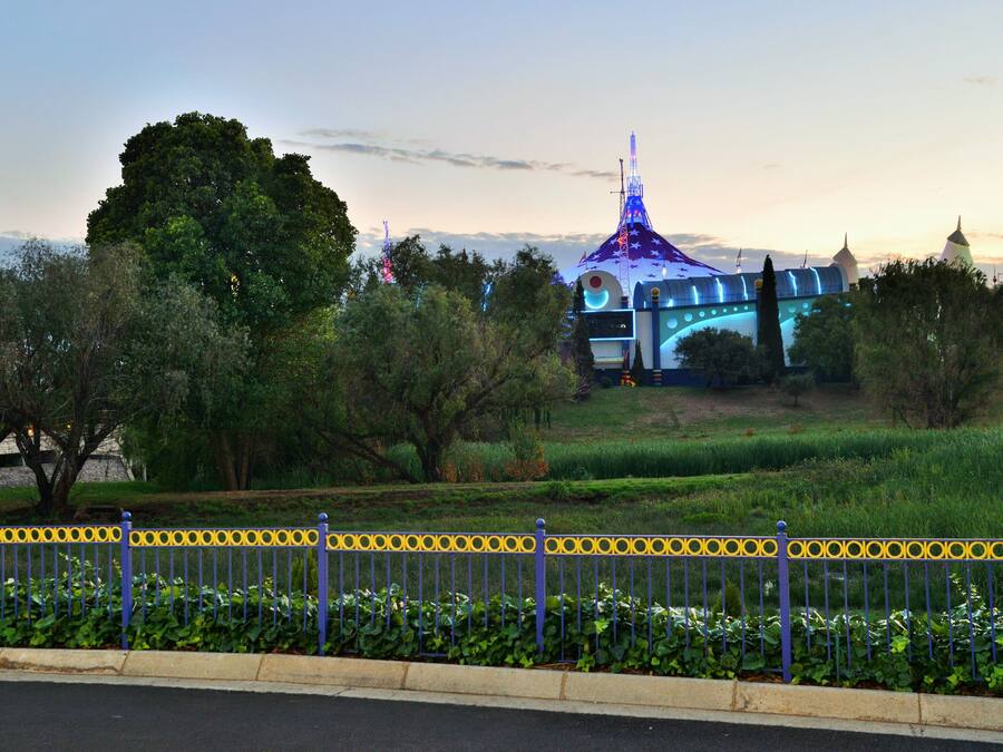 A building with a dome and a spire, surrounded by trees and a fence.