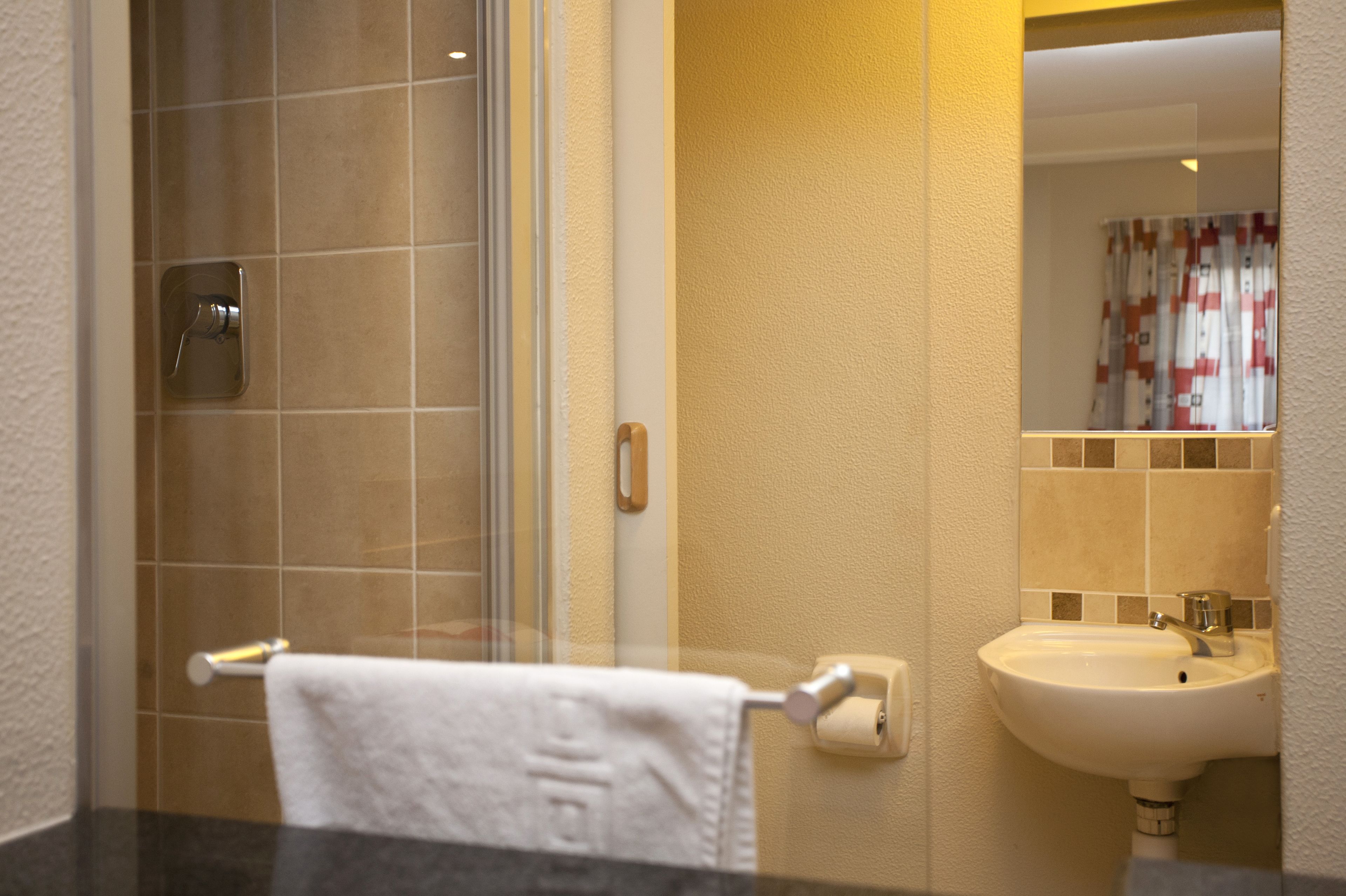 Un baño con cabina de ducha de vidrio, un lavabo blanco y un perchero para toallas.