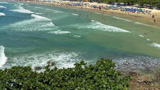 Un paysage urbain côtier avec de hauts immeubles, une plage avec des parasols et des vagues.