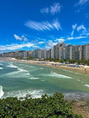 Un paisaje urbano costero con rascacielos, una playa con sombrillas y olas.