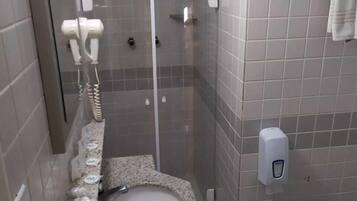 A bathroom with a granite sink, a glass shower enclosure, and a towel rack.