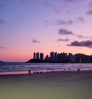 A beach with a city skyline in the background. - Grand Hotel Guaruja (Guarujá)