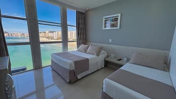 Quarto de hotel com duas camas, uma janela grande com vista para a cidade e um quadro pendurado na parede.