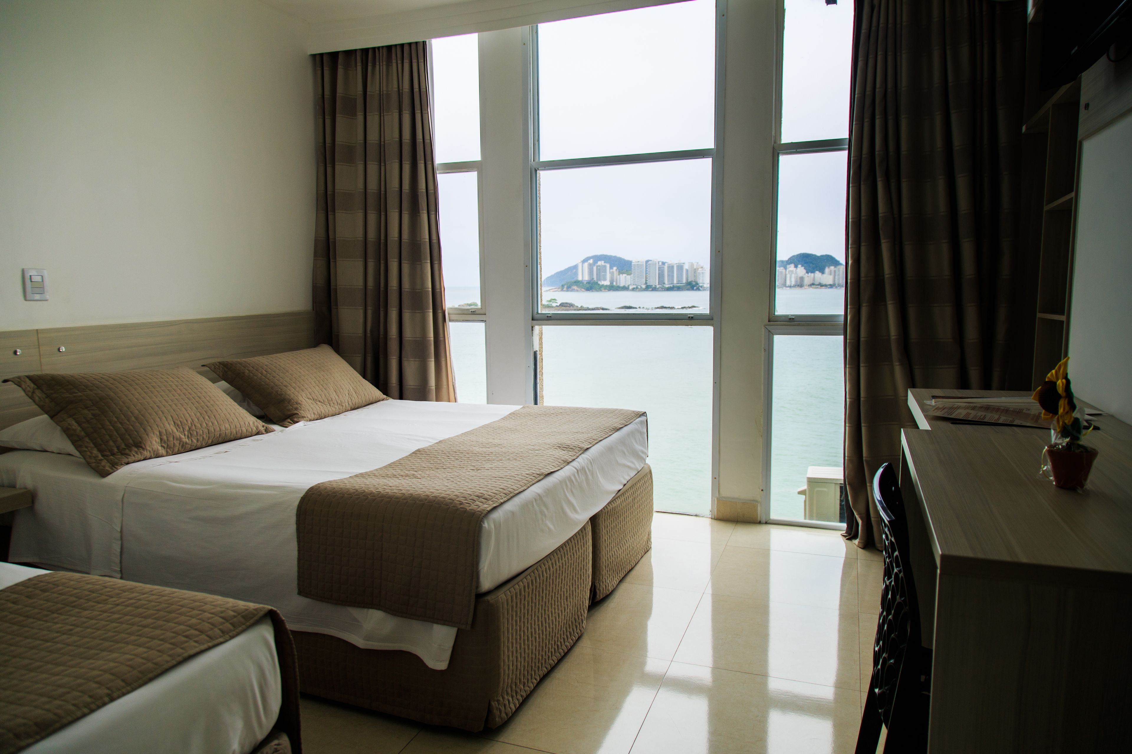 A hotel room with a large bed, a desk, and a view of a body of water and buildings.