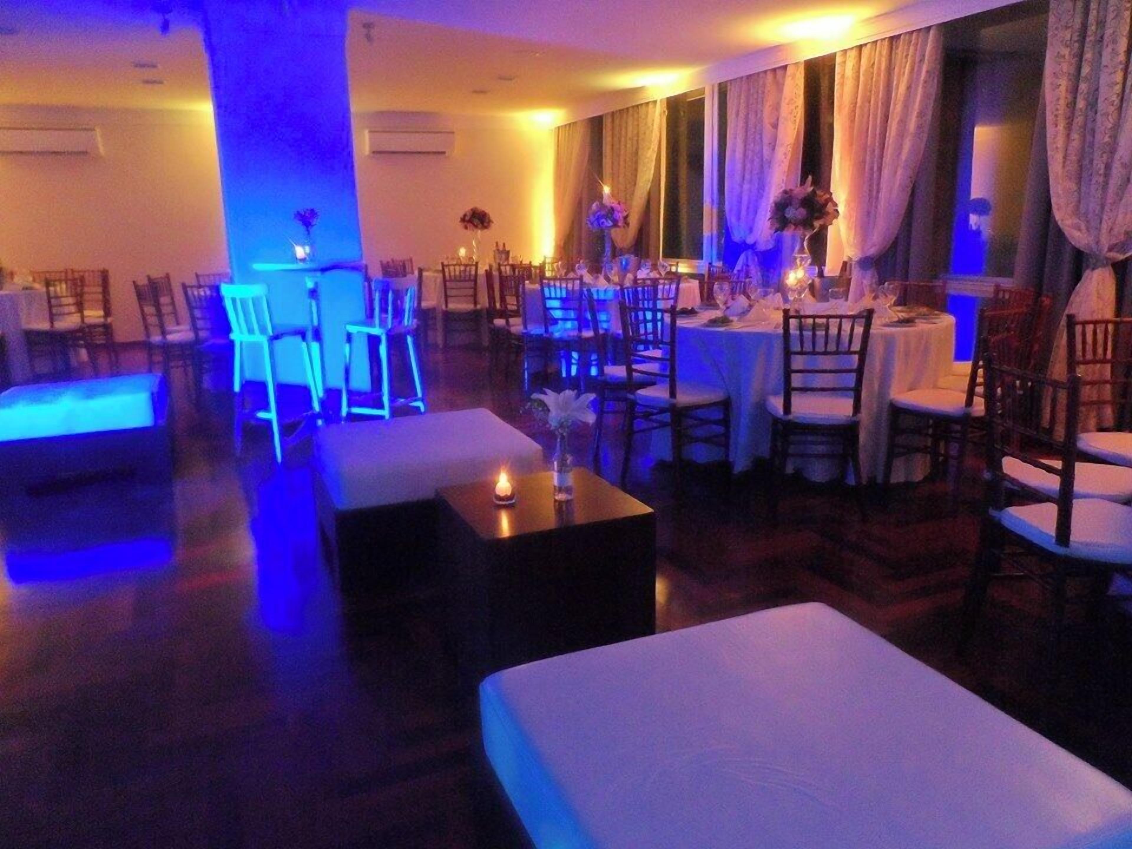 Un comedor de hotel con mesas dispuestas para el servicio, sillas alrededor y una zona de bar con taburetes.