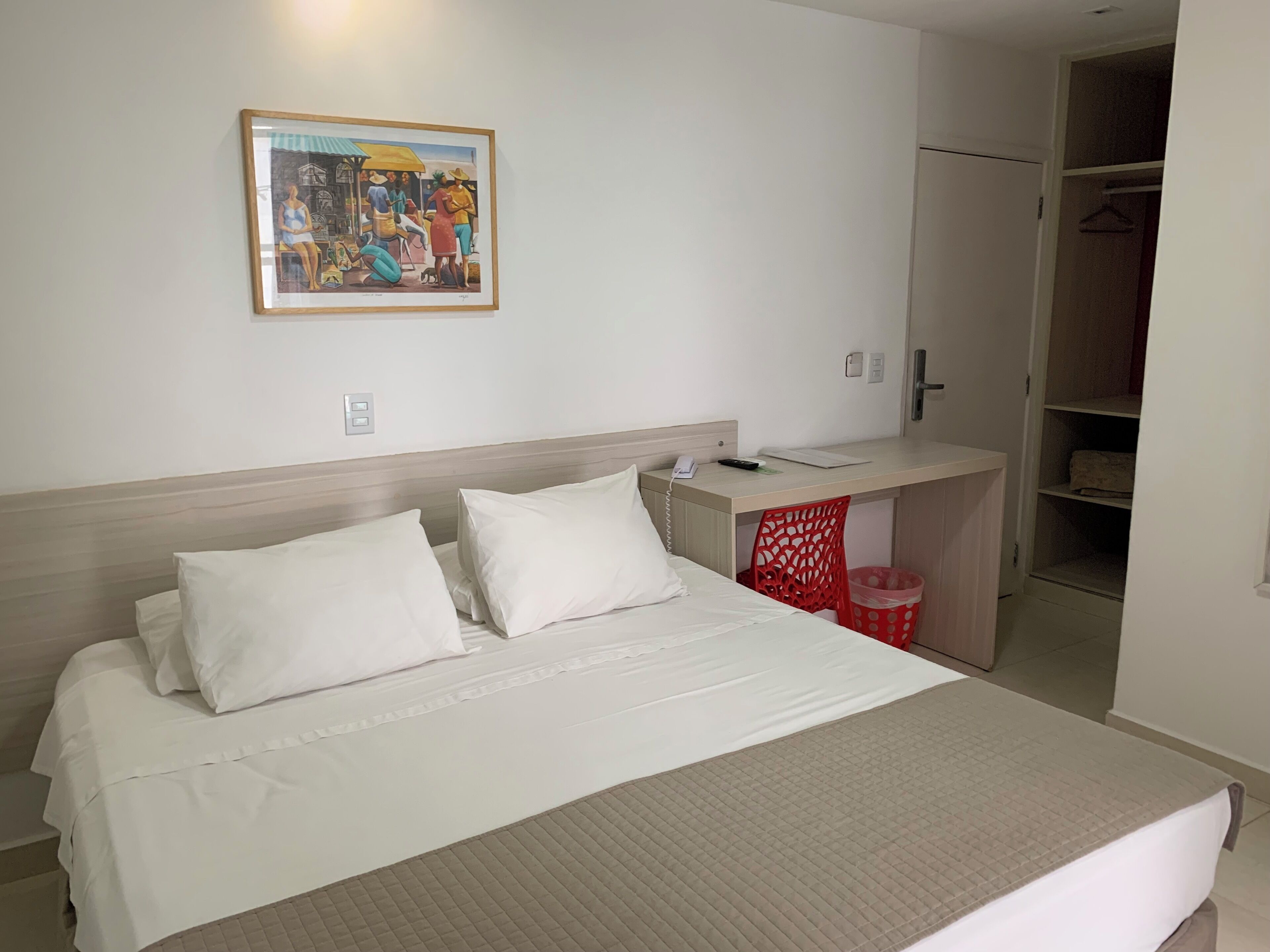 A hotel room with a bed, a desk, and a wardrobe.