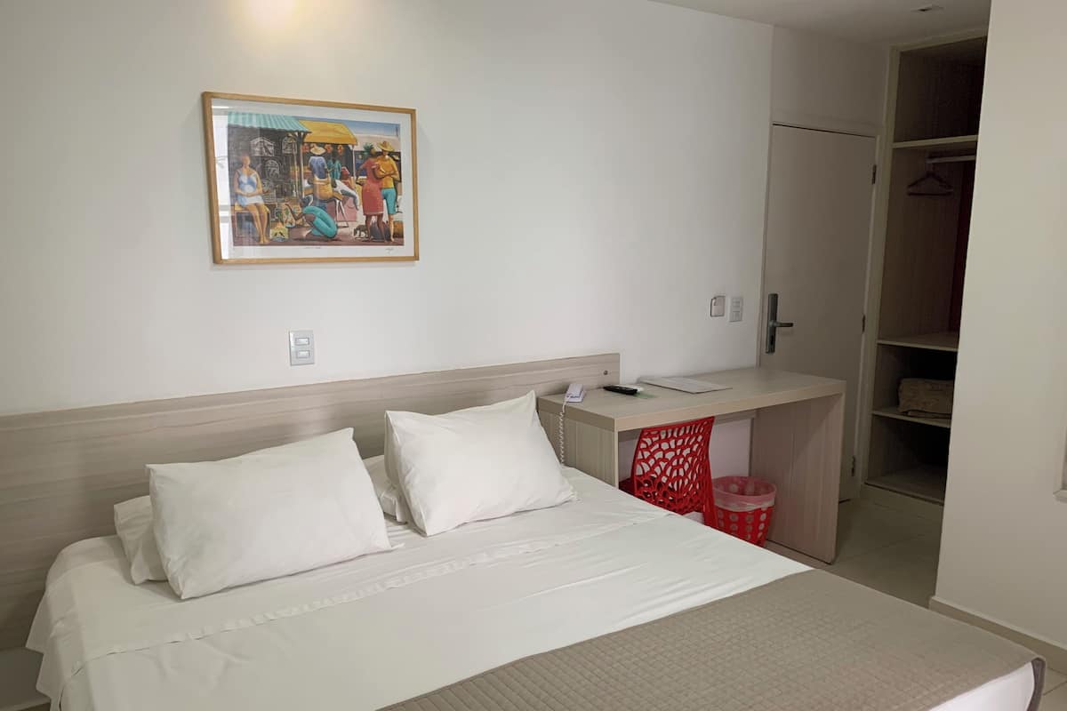 A hotel room with a bed, a desk, and a wardrobe.
