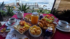 A breakfast spread on a table with a view of the ocean.