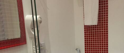 A bathroom with a red sink, a glass shower enclosure, a white toilet, and a red-tiled shower wall.