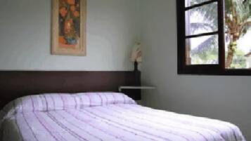 Een slaapkamer met een bed, een raam en een schilderij aan de muur.