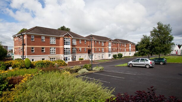 A multi-story brick building with a parking lot in front. - Courtbrack Accommodation - Hostel (Limerick)