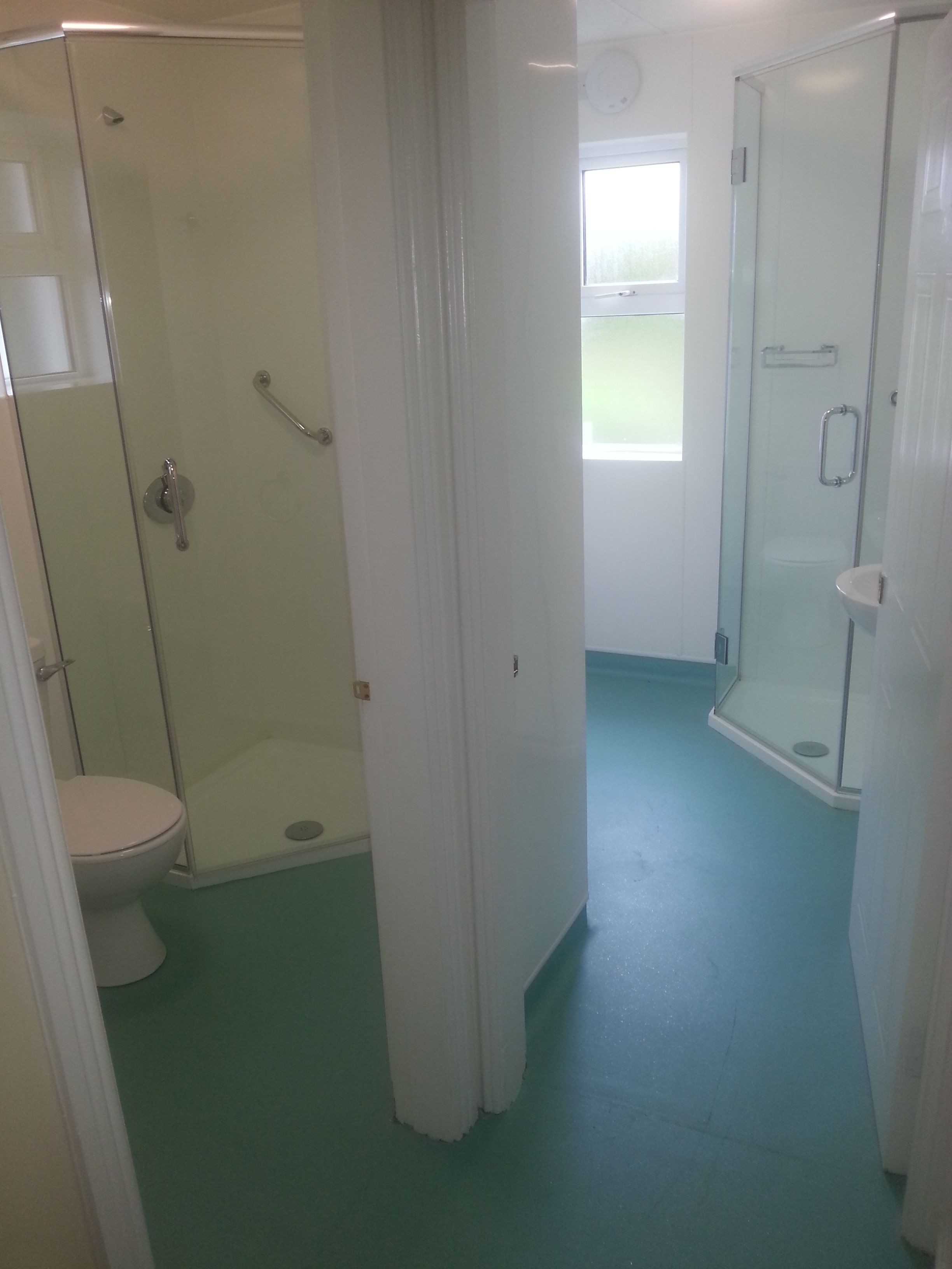 Un baño con cabina de ducha de vidrio, inodoro y lavamanos.