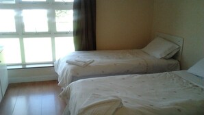 A room with two beds, a window with curtains, and a wooden floor. - Courtbrack Accommodation - Hostel (Limerick)