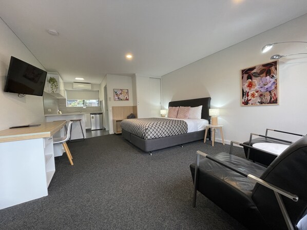 A modern hotel room with a bed, desk, chair, and a TV. - Coastal Motel (Apollo Bay)