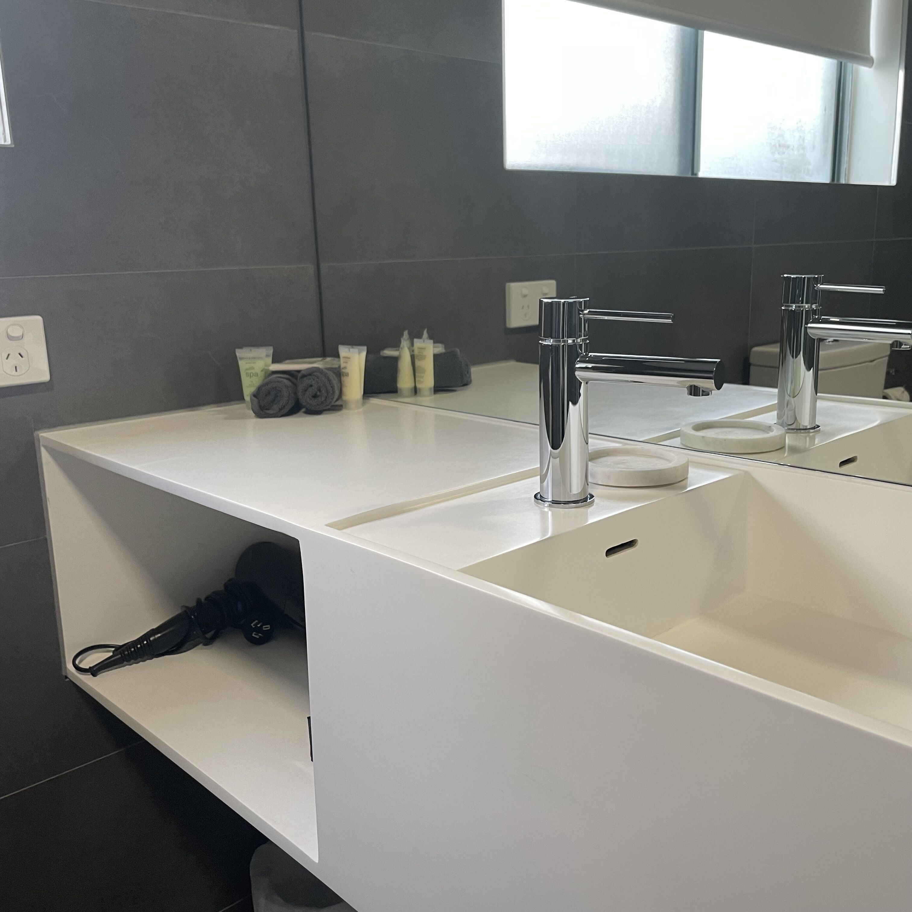 A modern bathroom with a white vanity, two sinks, and a large mirror.