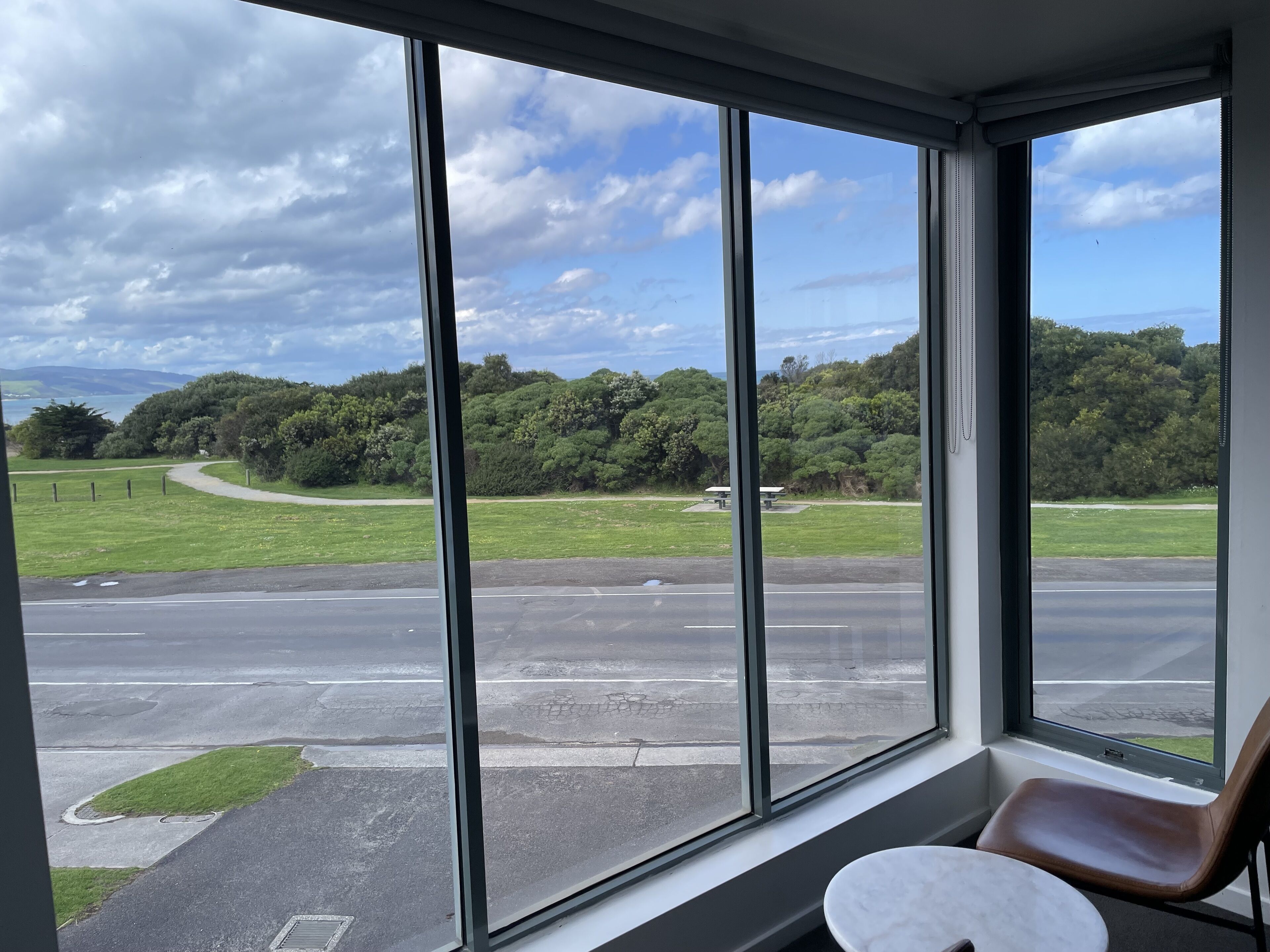 A room with large windows overlooking a road and greenery.